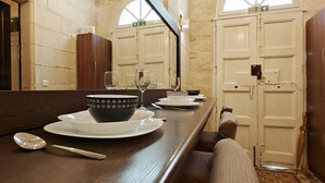 Un comedor con una larga mesa de madera preparada para dos personas, un espejo sobre la mesa y un suelo con diseño.