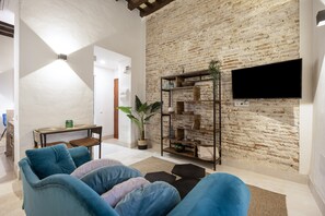 A living room with a brick wall, a flat-screen TV, a sofa, and a coffee table. - Apartment 'Bella Encantada' with Wi-Fi and Air Conditioning (Cádiz)