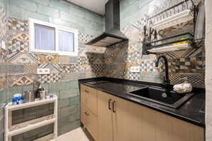 A kitchen with patterned tiles, a black countertop, wooden cabinets, a window, and a dish rack. - Apartment 'Bella Encantada' with Wi-Fi and Air Conditioning (Cádiz)