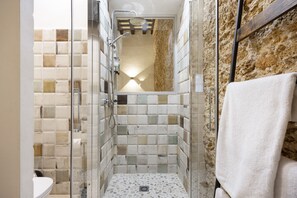 Une douche avec des portes en verre, un mur carrelé et une serviette accrochée au mur.