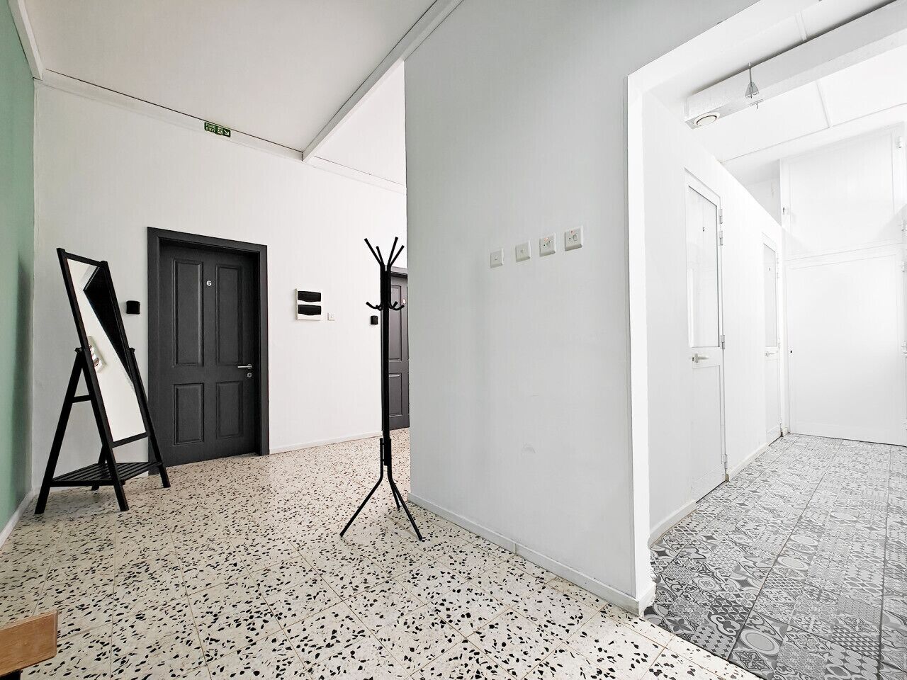 A hallway with a black door, a whiteboard stand, and a tripod.