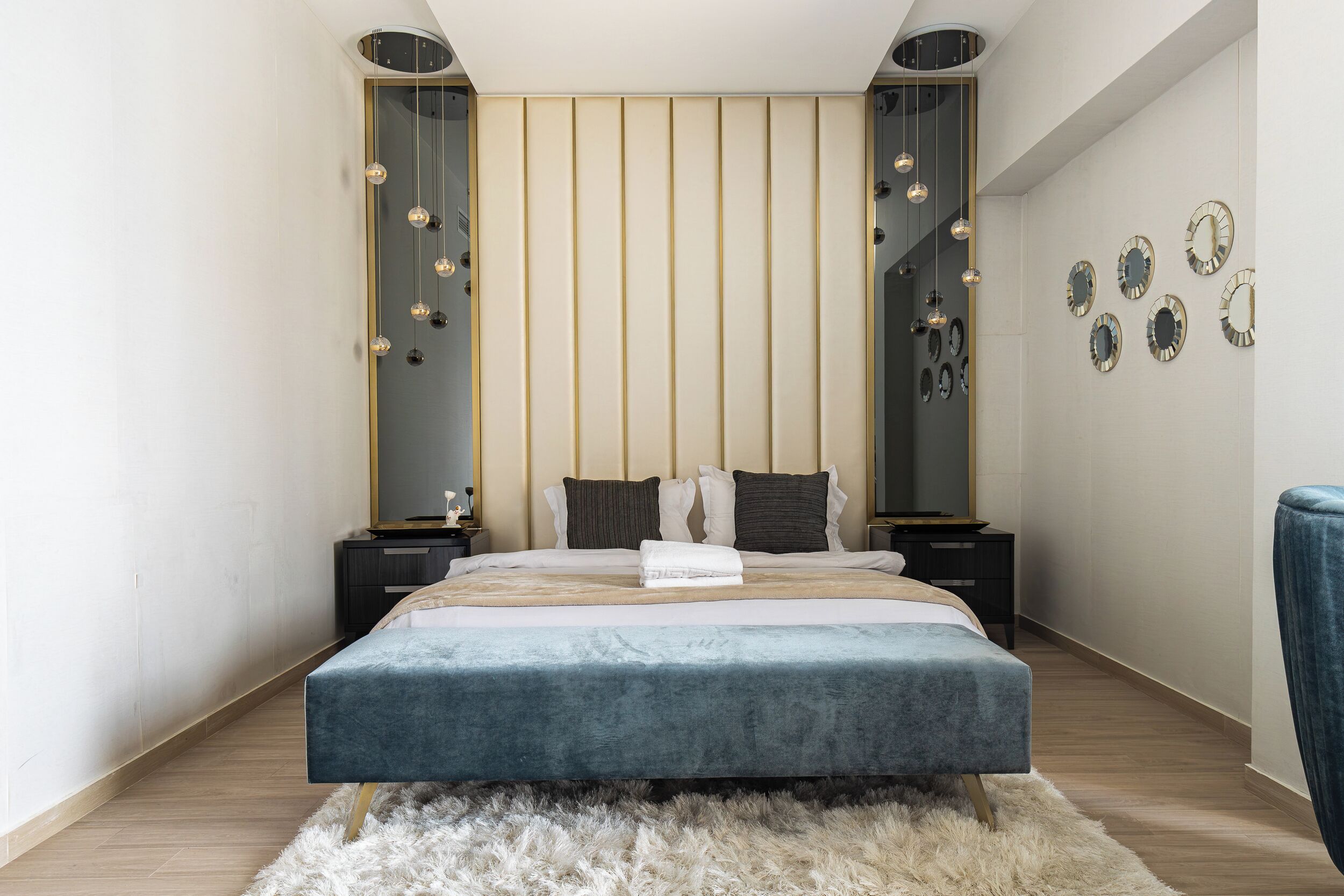 Une chambre moderne avec un grand lit, des tables de chevet, un tapis moelleux et des miroirs fixés au mur.