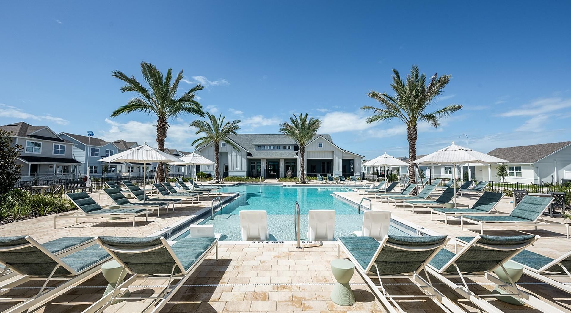 A pool area with lounge chairs and palm trees.
