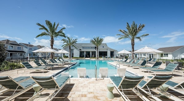 A poolside area with lounge chairs, palm trees, and a clear blue sky. - Landing Apartments - Four Corners (Kissimmee)