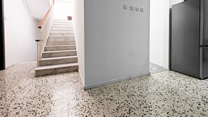 A modern kitchen with a stainless steel refrigerator, a staircase leading to a bright area, and a speckled floor. - Cosy room 7  1 bedroom (Pietà)