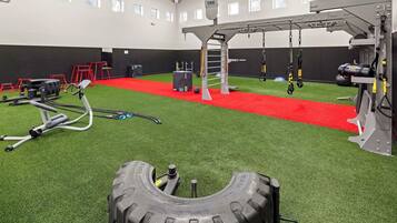 A gym with artificial turf, weightlifting equipment, and a red carpet.