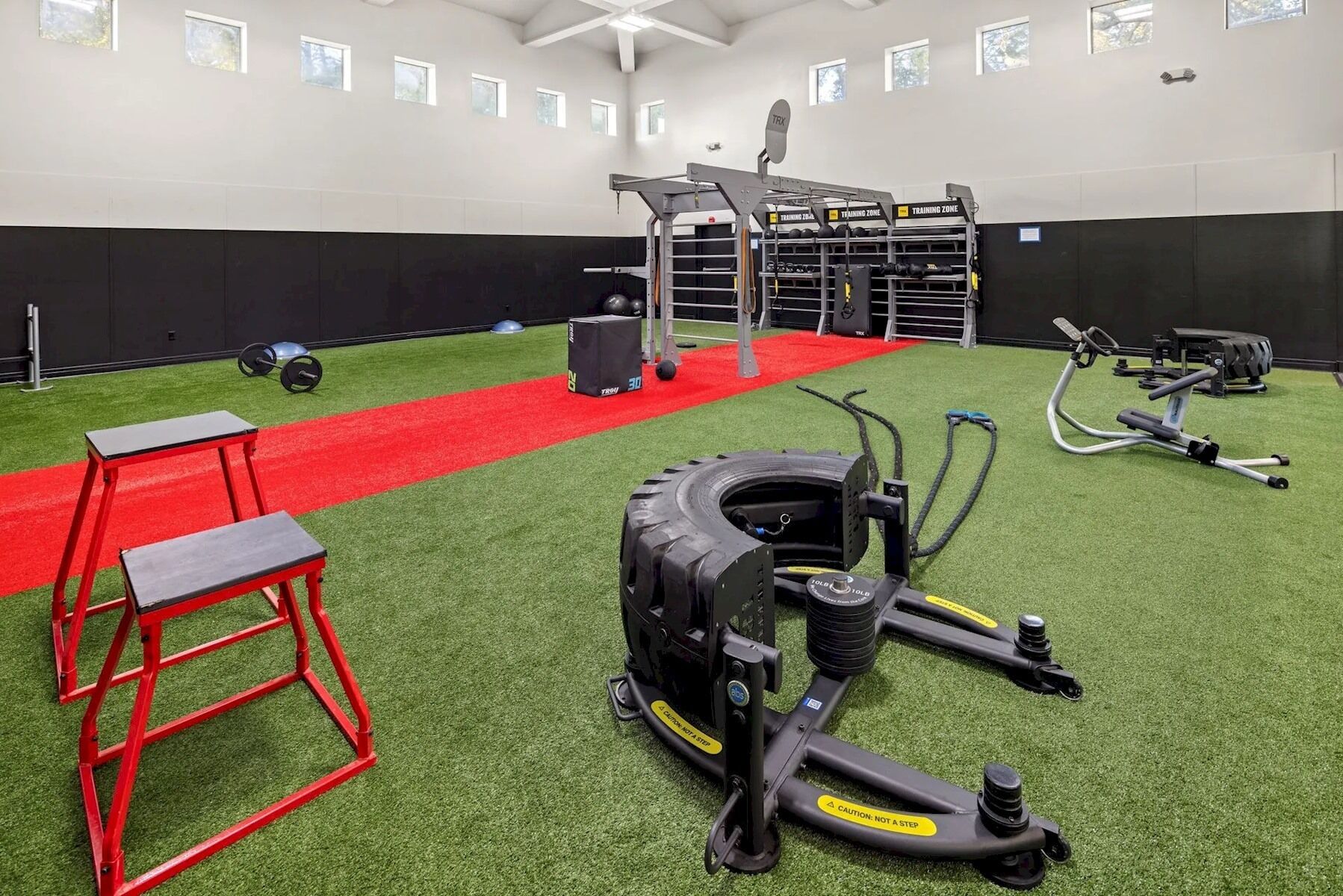 A gym with a red carpet, exercise equipment, and a weightlifting area.