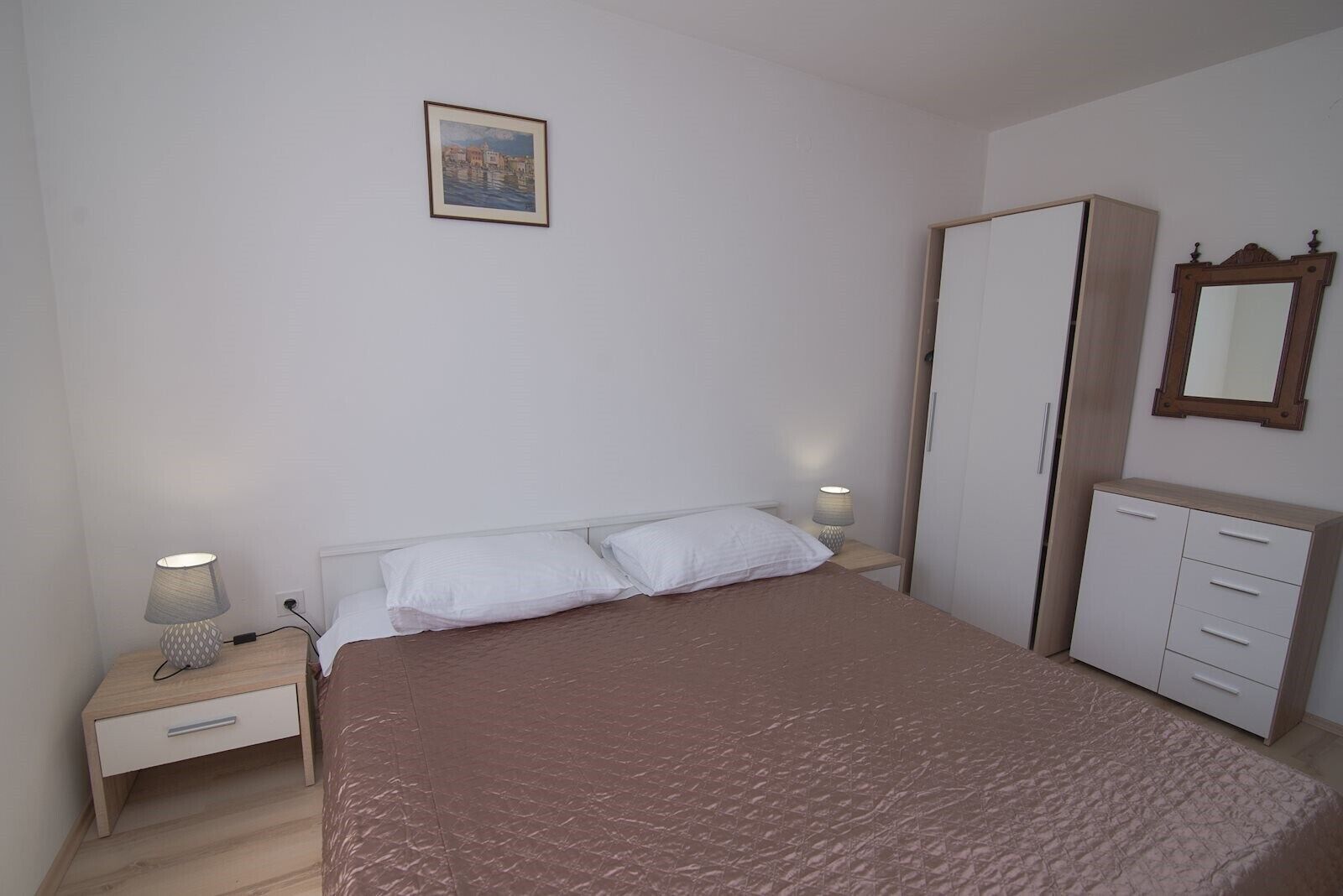 A bedroom with a bed, bedside tables, a wardrobe, and a mirror.