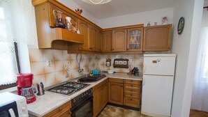 Une cuisine compacte avec des meubles en bois, une cuisinière à gaz, un four encastré et un réfrigérateur blanc.