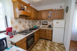 Eine kompakte Küche mit Holzschränken, einem Gasherd, einem Backofen und einem weißen Kühlschrank.