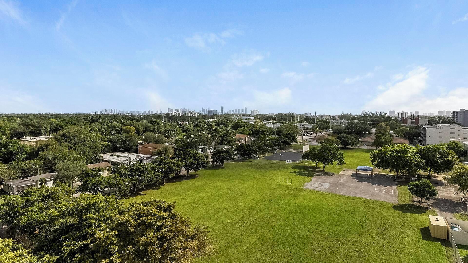 Un quartier résidentiel avec un grand parc verdoyant, des maisons et, au loin, la silhouette de la ville.