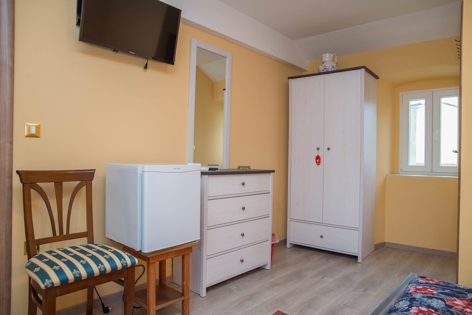 Ein Zimmer mit einem Bett, einem Schreibtisch, einem Stuhl, einem Kleiderschrank und einem Fernseher.