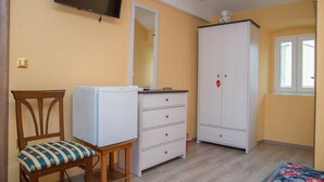 Ein Zimmer mit einem Bett, einem Schreibtisch, einem Stuhl, einem Kleiderschrank und einem Fernseher.