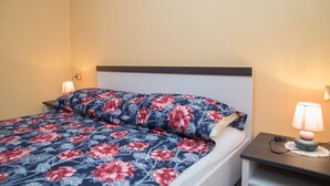 Ein Bett mit floraler Bettwäsche, zwei Nachttischlampen und ein Nachttisch mit Lampe.