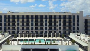 Ein mehrstöckiges Hotel mit einem zentralen Innenhof, der einen Swimmingpool beherbergt und von Balkonen umgeben ist.