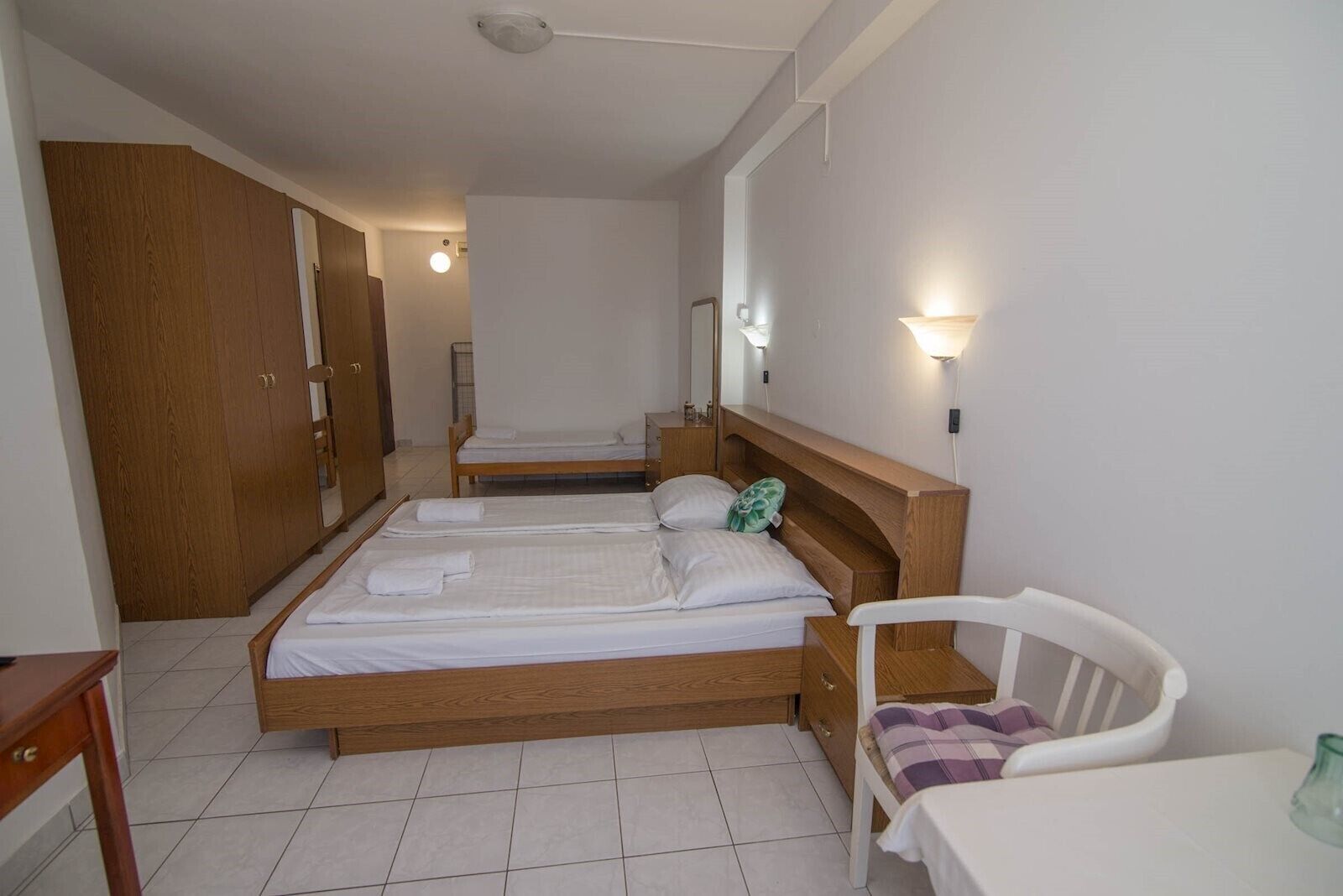 Ein Schlafzimmer mit zwei Betten, einem Holzschrank, einem Nachttisch und einem Stuhl.
