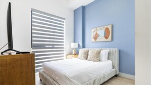 Ein Schlafzimmer mit Bett, Schreibtisch, Stuhl, Lampe und einem Gemälde an der Wand.