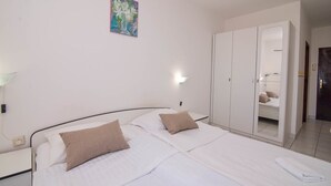 A hotel room with two beds, a wardrobe, a bedside lamp, and a painting on the wall. - Sv. Martin / B&B sv Martin C, pogled na more (Mali Lošinj)