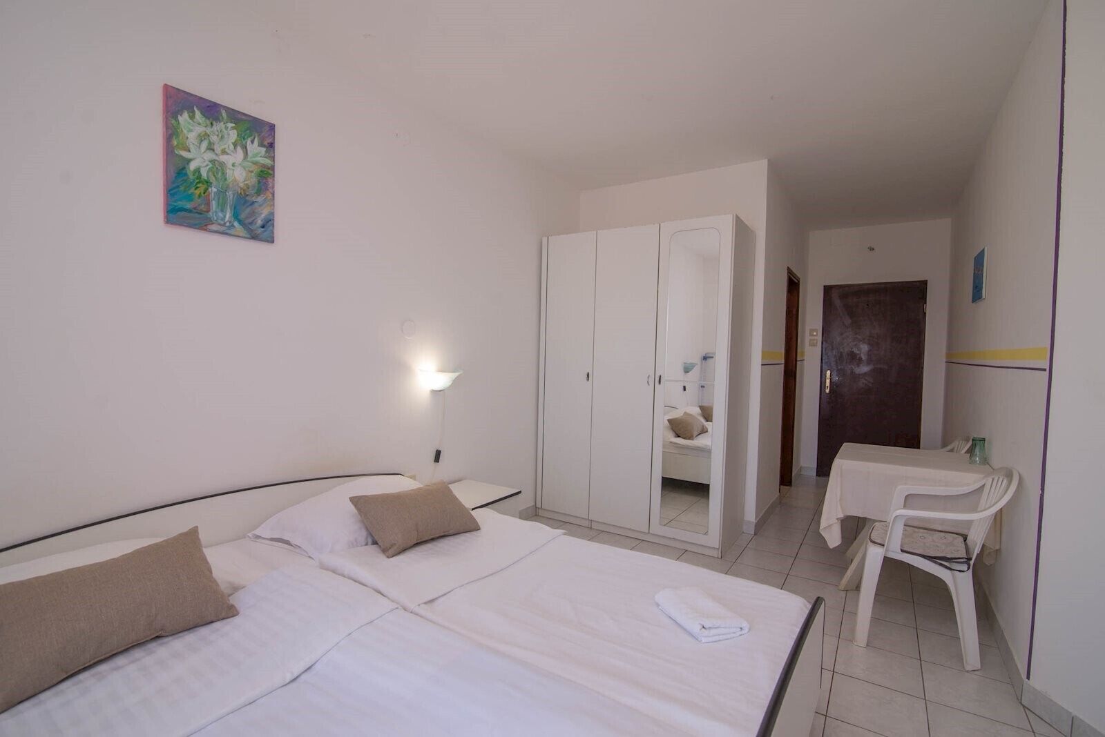 Ein Hotelzimmer mit Bett, Schreibtisch, Kleiderschrank und einem Bild an der Wand.