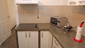 A kitchen with a built-in stove, microwave, and toaster. There is a white door and a countertop with a red object. - Mariana / Mariana A3 (Veli Lošinj)
