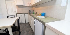 Een koelkast, een oven, een kookplaat, kookgerei, borden en bestek