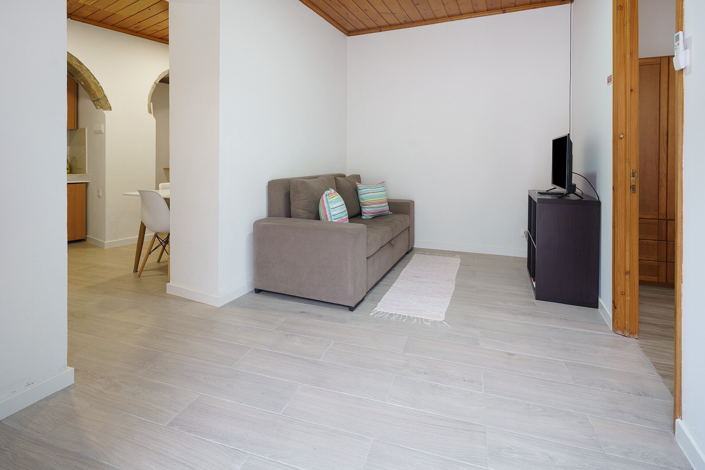 Un salon avec un canapé, un téléviseur et un tapis.