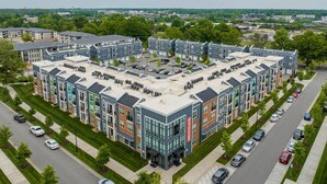 A modern apartment complex with multiple buildings, parking spaces, and a well-maintained lawn. - Landing | Amazing 1BD, Clubhouse, Pool (Charlotte)