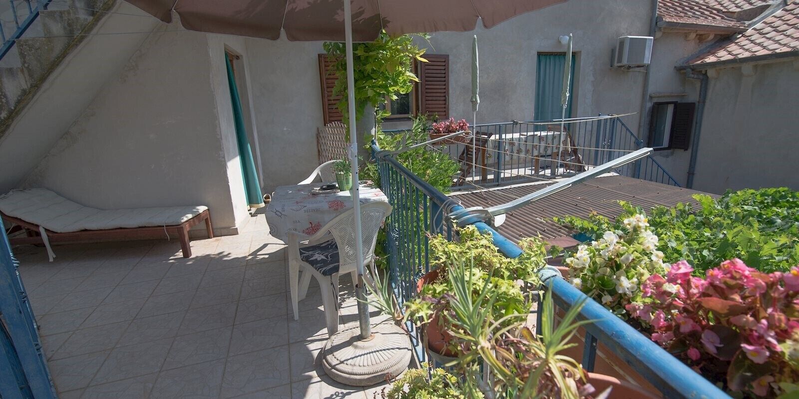 Un balcón con una silla, una mesa y plantas en macetas.