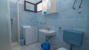 Een badkamer met een douche, wastafel, kast en een spiegel.