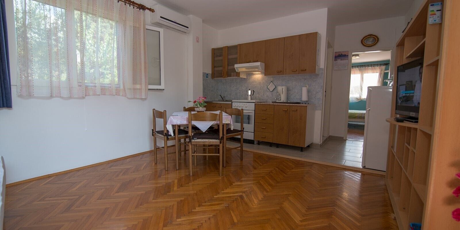 Une cuisine de taille réduite avec des meubles de rangement en bois, une table à manger avec des chaises et un réfrigérateur.