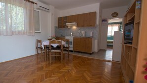 Een compacte keuken met houten kastjes, een eettafel met stoelen en een koelkast.