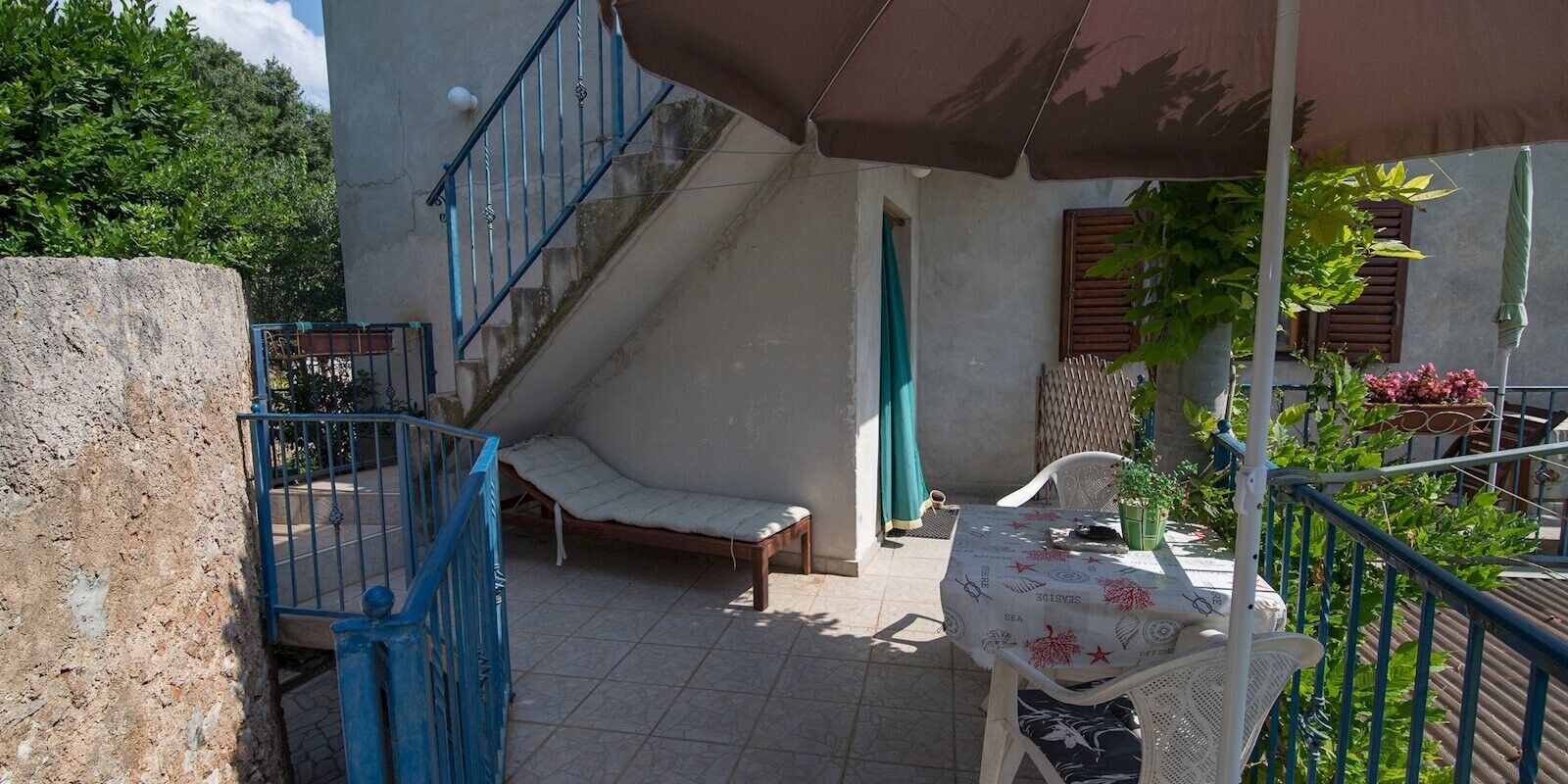 Eine Terrasse mit Tisch, Stühlen, einer Treppe und einem Geländer.