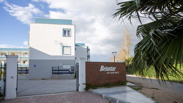 A gated entrance to a residential building named Betastar Residence with a paved driveway and a palm tree in the foreground. - Stromboli Sunset with shared pool (Villaggio del Golfo)