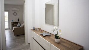 A modern bathroom with a wooden vanity, a large mirror, and a potted orchid. - Stromboli Sunset with shared pool (Villaggio del Golfo)