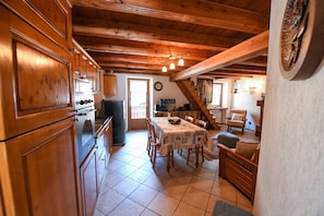 A wooden interior with a dining table, chairs, and a kitchen area.