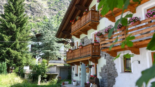 A traditional chalet with wooden balconies, stone walls, and potted flowers. - 'Maison Elie' Apartment with Mountain View, Balcony and Wi-Fi (Vieyes   Aymavilles)
