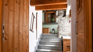 A wooden staircase leading to a stone wall, a small wooden table, and a door. - 'Maison Elie' Apartment with Mountain View, Balcony and Wi-Fi (Vieyes   Aymavilles)