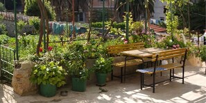 Een tuin met een houten bank en planten in potten.