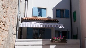 A building with a white facade, blue shutters, and a striped awning. - Pinea / Pinea A2 in Veli Lošinj (Veli Lošinj)