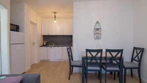 A compact kitchen with white cabinets, a microwave, and a small island. There is a dining area with a table and four chairs. - Pinea / Pinea A2 in Veli Lošinj (Veli Lošinj)