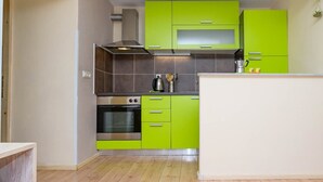 Eine kleine Küche mit grünen Schränken, einem Edelstahlbackofen und einer Mikrowelle.