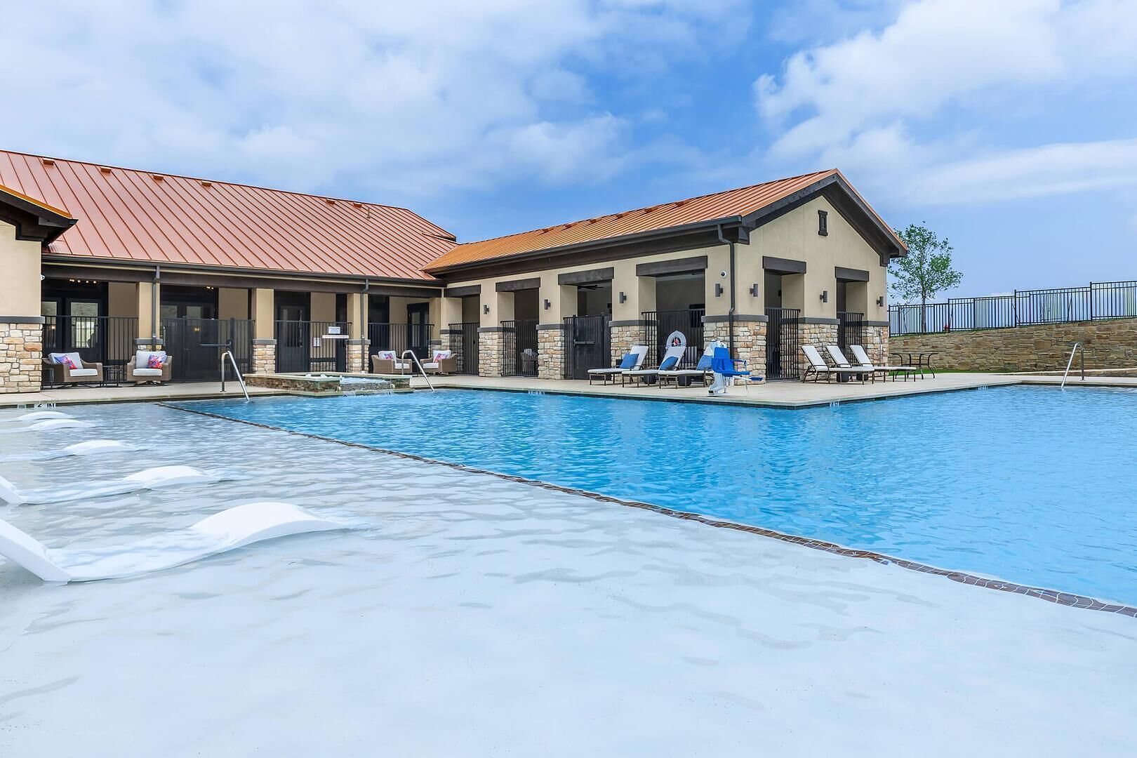 Un hotel con piscina, mobiliario exterior y un patio cubierto.