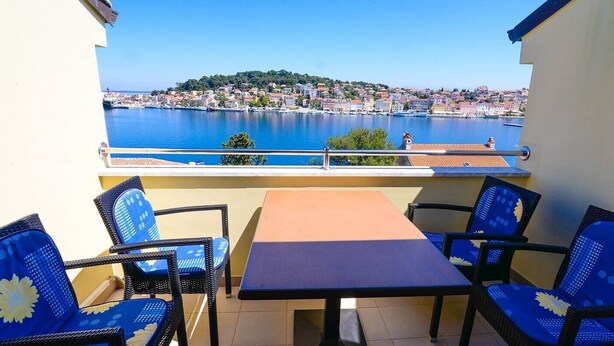 A balcony with a table and chairs, overlooking a harbor with a town in the background. - Frantin / Frantin B4 (Mali Lošinj)