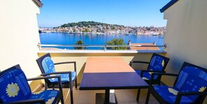 Ein Balkon mit Tisch und Stühlen, der auf einen Hafen mit einer Stadt im Hintergrund blickt.
