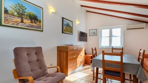 Une pièce comprenant une table à manger, des chaises, un canapé, un meuble en bois et un téléviseur fixé au mur.