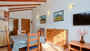 Un coin repas comprenant une table, des chaises, des meubles en bois et un téléviseur à écran plat fixé au mur.