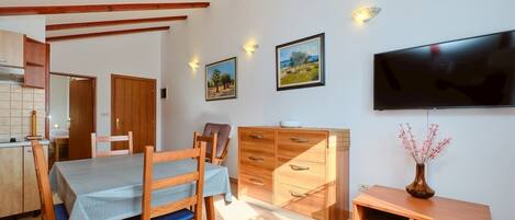 A dining area with a table, chairs, wooden cabinets, and a flat-screen TV mounted on the wall.
