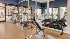 A gym with various exercise equipment, including dumbbells and weight machines. - Landing | Modern 1BD, Pool, Gym (Houston)