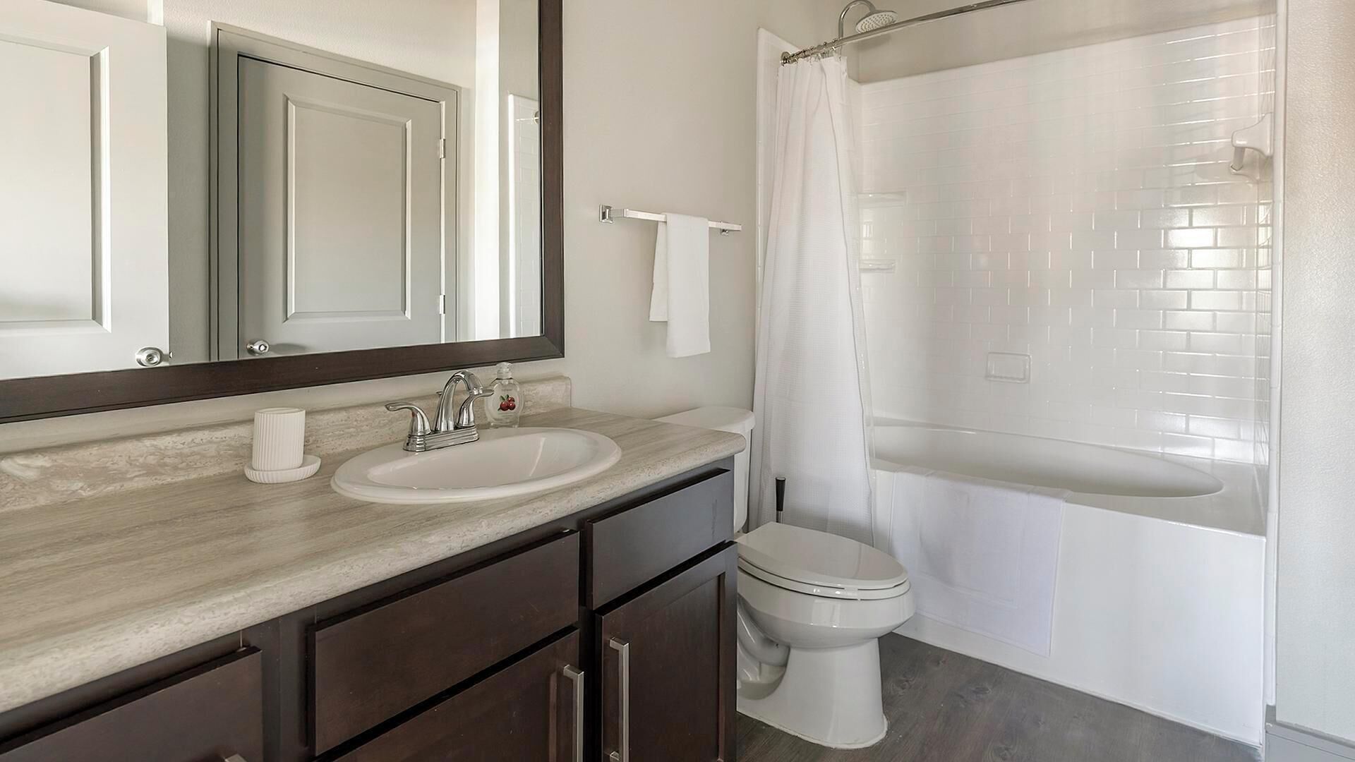 A bathroom with a sink, mirror, toilet, and shower.