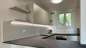 A modern kitchen with a dark marble countertop, built-in appliances, and a window with a view of greenery. - Villa Venezia Garda: Lake View, Garden & Jacuzzi (Garda)